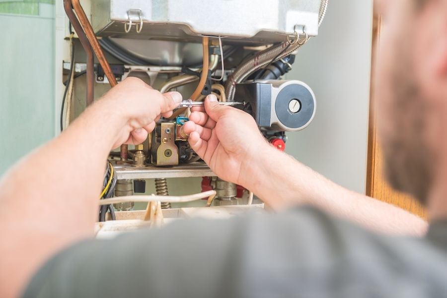 Image of someone working on a furnace. Why is my furnace leaking water?