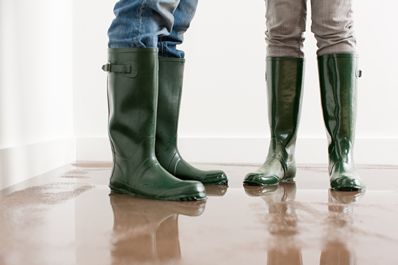 How to Winterize Your Pipes. Young couple in wellington boots on flooded floor.