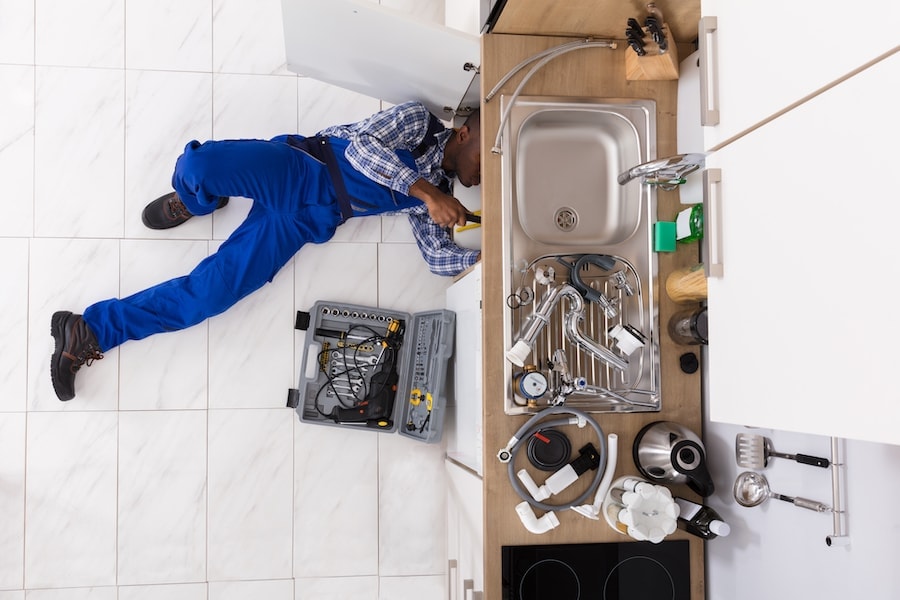 How Can a Plumber Help With My Well? Image shows plumber working under sink.