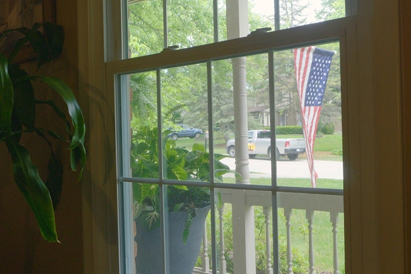 Video - Energy Saving Tip 5. Window looking out to yard with hanging American flag.