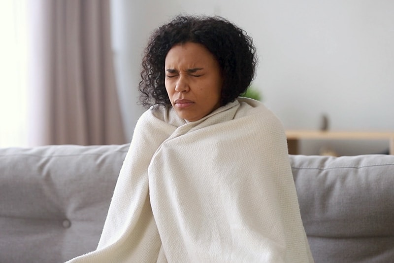 Woman Under a Blanket Indoors. Video - Upgrade Your Furnace.