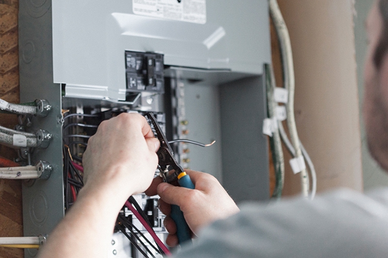 When to Upgrade Your Electrical Panel. Hands working on an electrical panel.