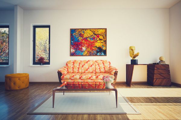 photo of a living room with an orange couch in the middle. Photos on the wall above a table in the background.