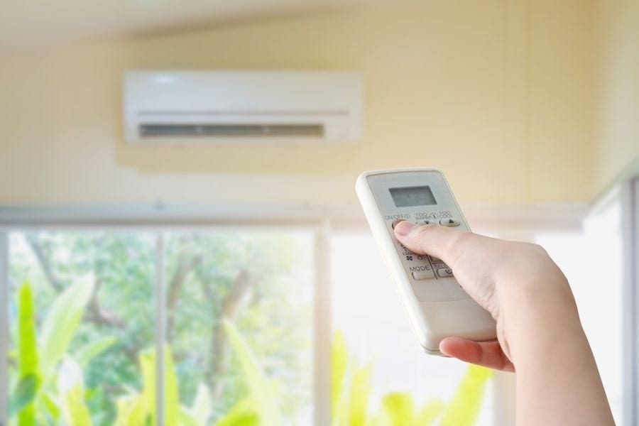 Image of someone using a remote on a ductless system. Ductless Mini Splits for Comfortable and Healthy Living.