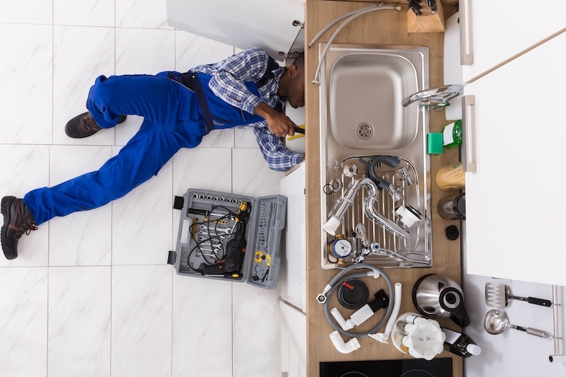 Why Is My Garbage Disposal Humming? Plumber repairing kitchen sink.